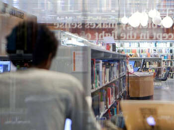 2 personer jobber i et bibliotek med bokhyller i bakgrunnen