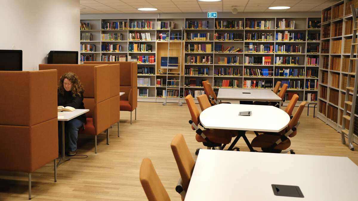 Arbeidsplasser i biblioteket, student sitter og leser.
