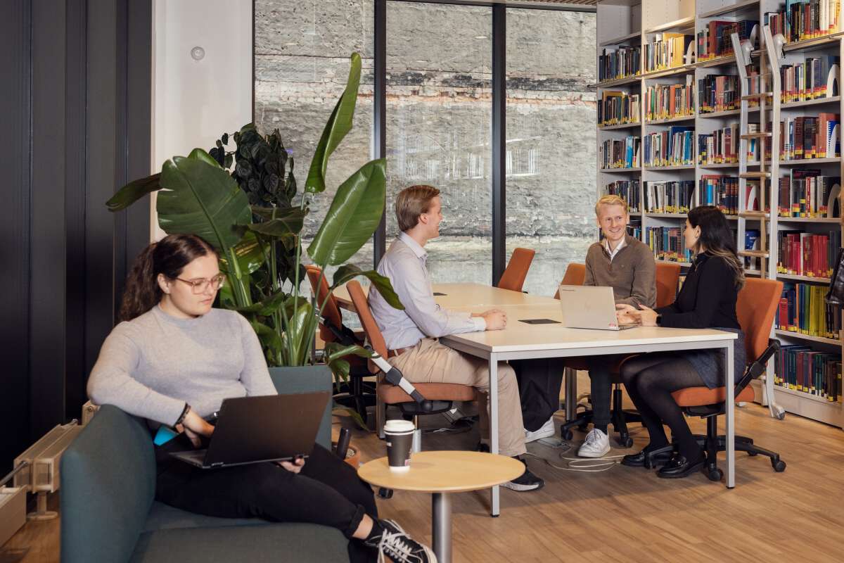 Student som leser, andre studenter som jobber i bakgrunnen.