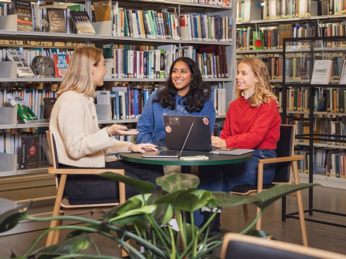 Studenter rundt et bord i biblioteket.