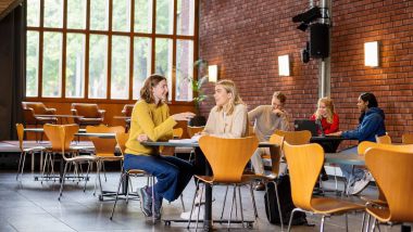 Studenter rundt et bord i foajeen.