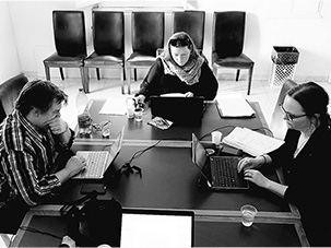Three people sitting round a table, working.
