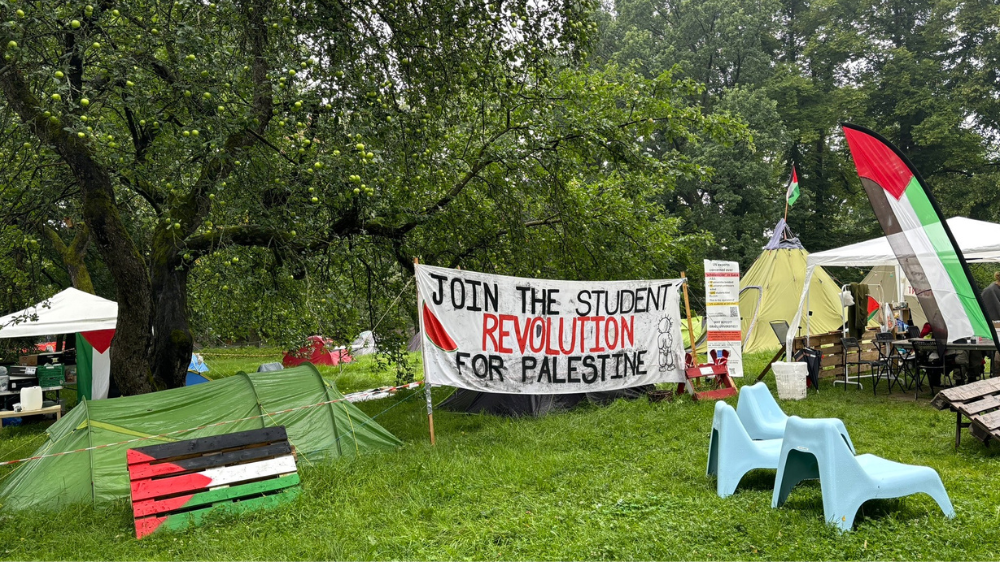 Bilde av telt, utestoler og et banner med tekst.