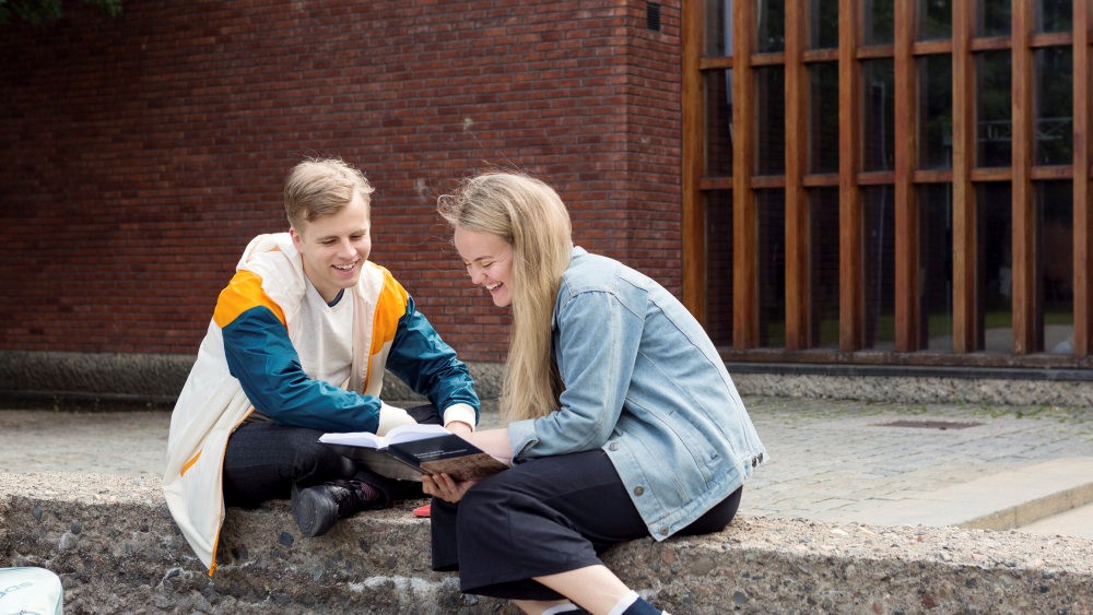 Two students reading a book together.